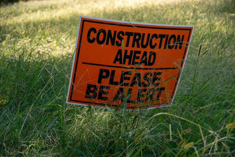 a sign sitting on the ground next to some grass