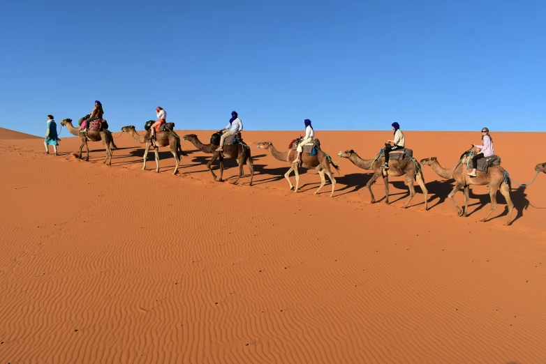 a group of people riding on top of three camels
