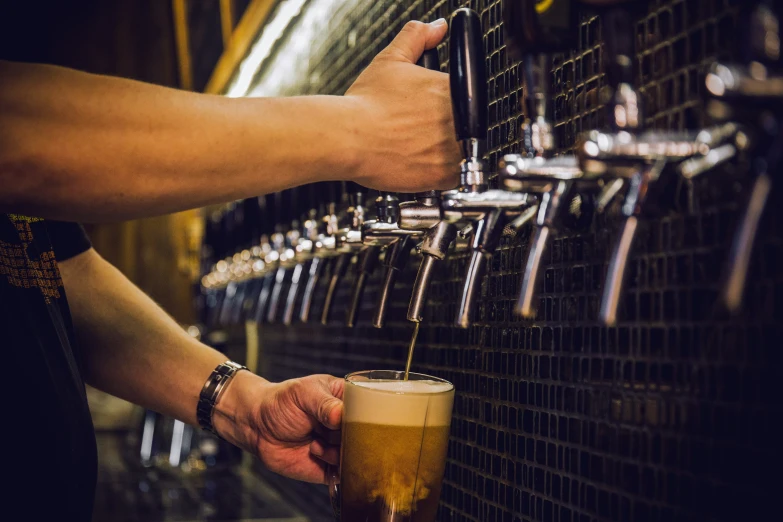 a man pours beer from a keg into a glass at a craft brewery