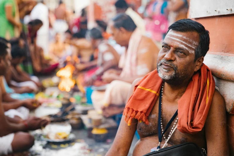 an indian man in traditional clothing sits with his food on the side of a street