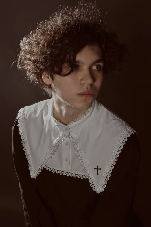 a woman with curly hair, a collared blouse and cross on the neck