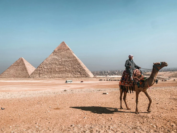 a man riding a camel near the great pyramids in egypt