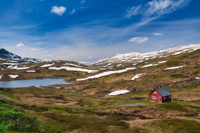 a red house on a hill overlooking a body of water