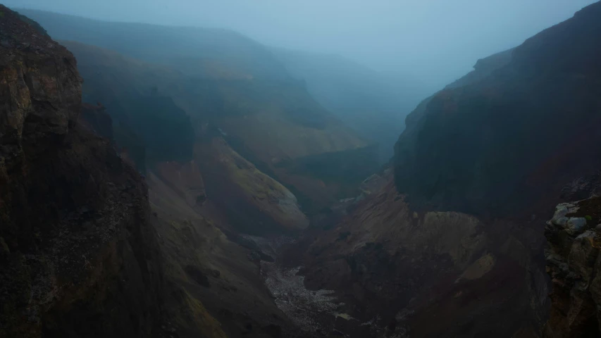 a foggy, dark, and scenic valley with some cliffs