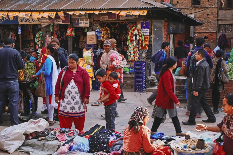 people walking and sitting on the ground in front of shops