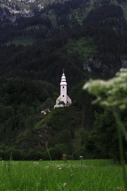 a small white church in the middle of a green field