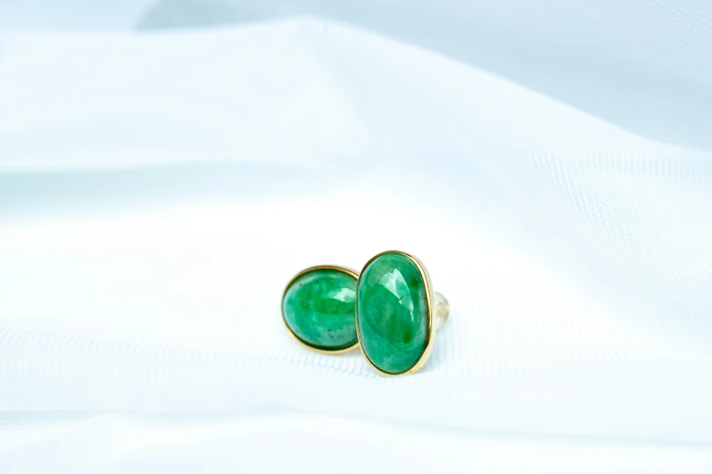 the front and back view of two green oval caballons in gold