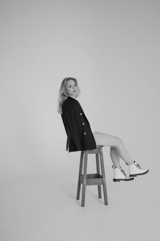 black and white pograph of a woman on a stool