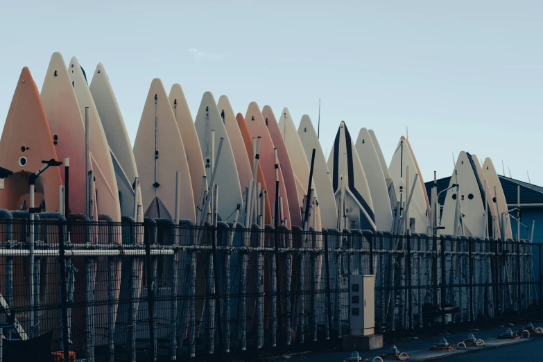 a bunch of surfboards that are all leaning up against a fence