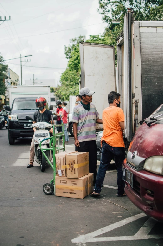 two men hing a fork with a box behind them on the back of the truck