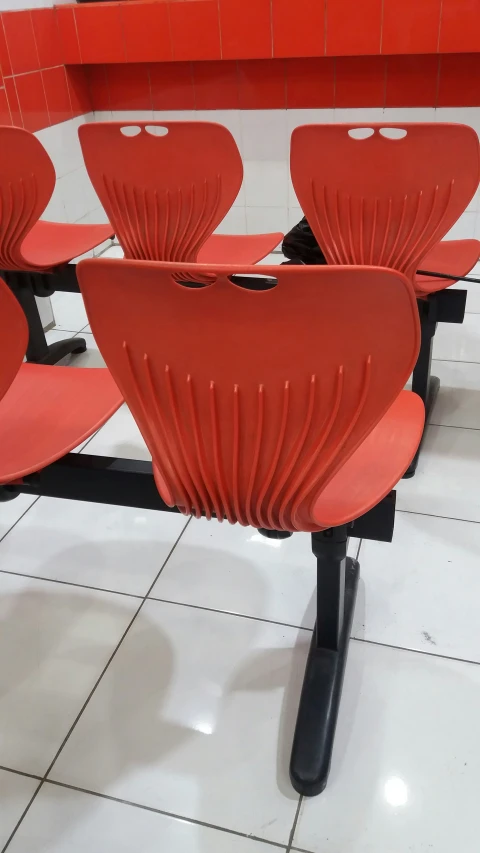 six red chairs arranged together on either side of a white floor