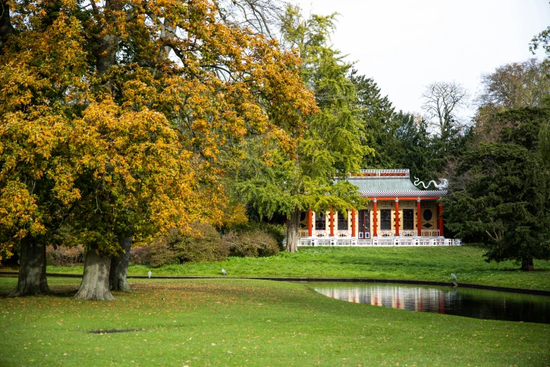 a gazebo sits near a pond in a grassy park