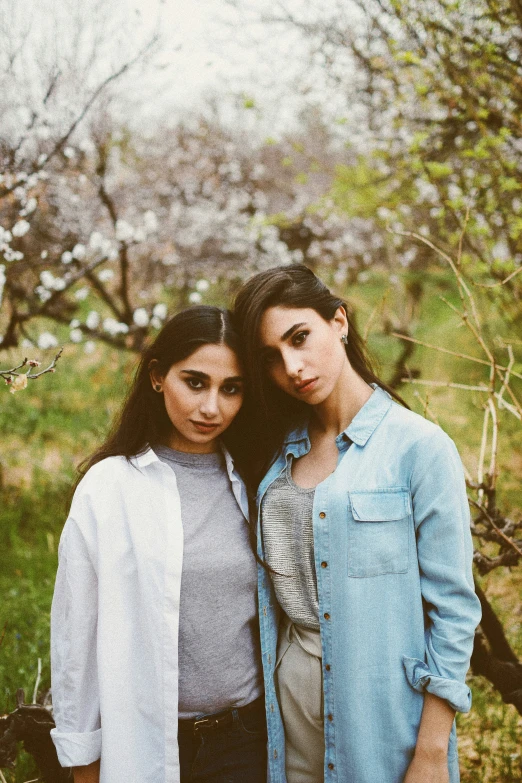 two young women posing for a pograph in an apple orchard