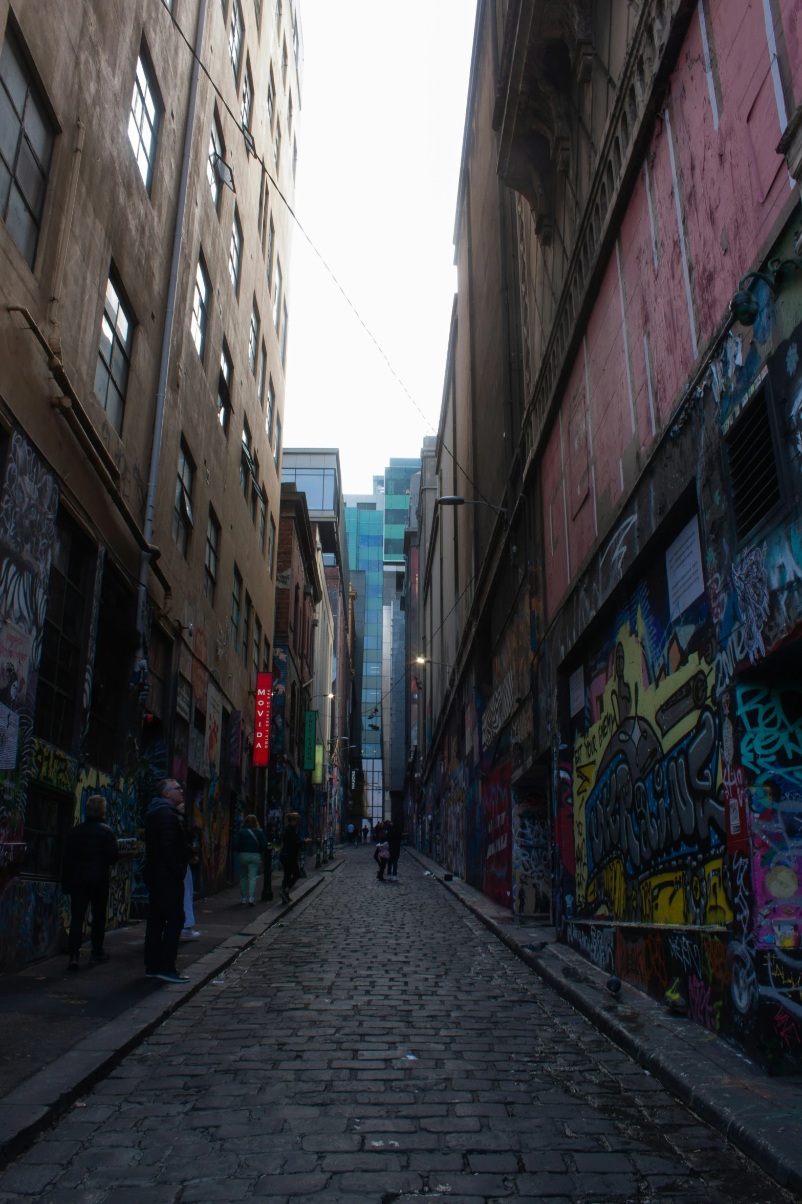 an alley way with people walking around and graffitti