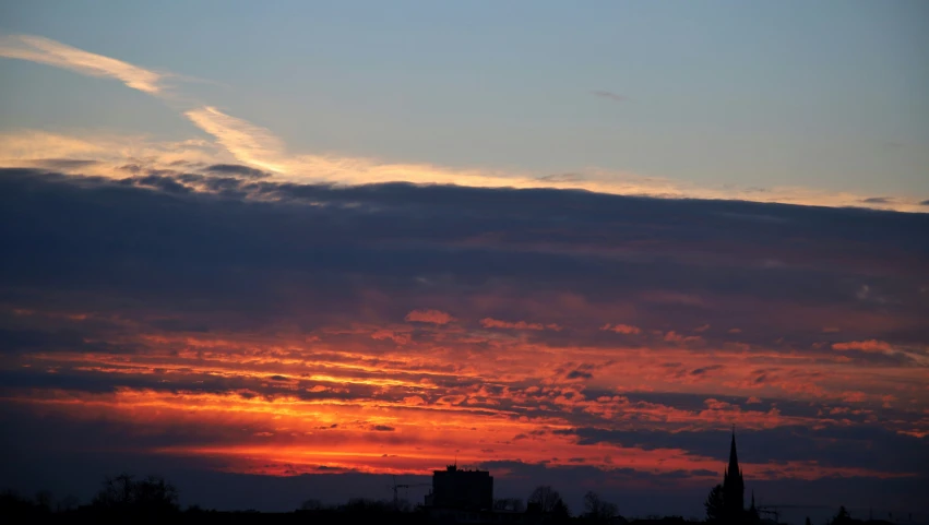 a cityscape in the distance with buildings in the background and a red cloud above it