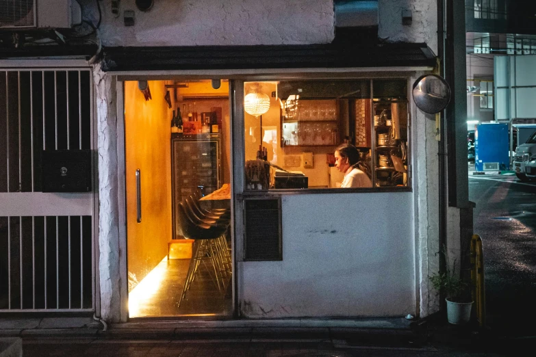 a man standing inside of a small business window at night