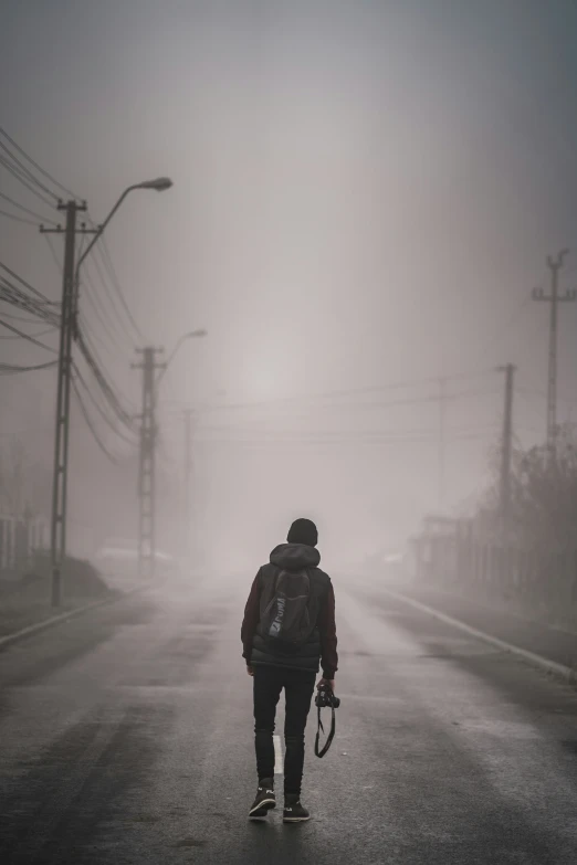 a person in black jacket walking with back pack and a camera