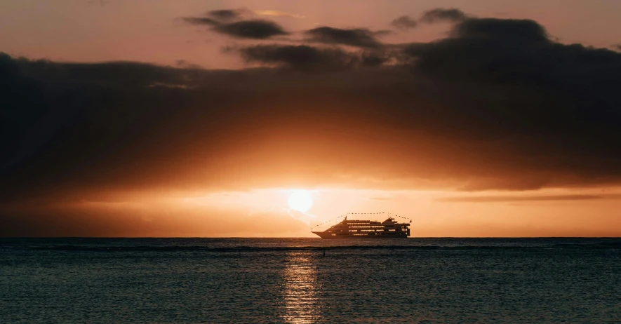 a large passenger ship on the ocean under a cloudy sky