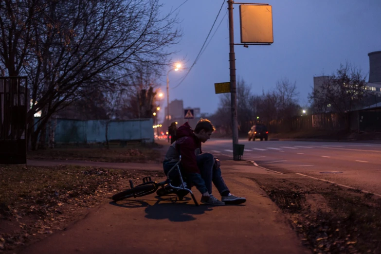 two men sitting on a bike by the side of a road