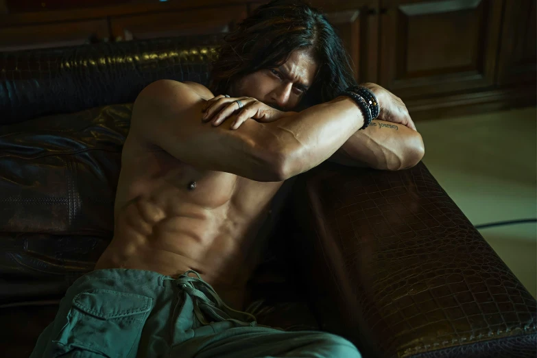 a shirtless man laying on top of a brown couch