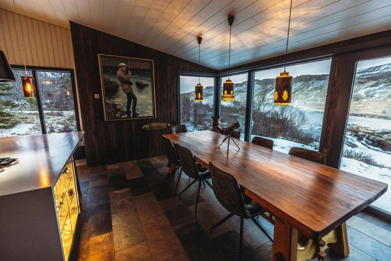 a wooden table surrounded by chairs with a huge window