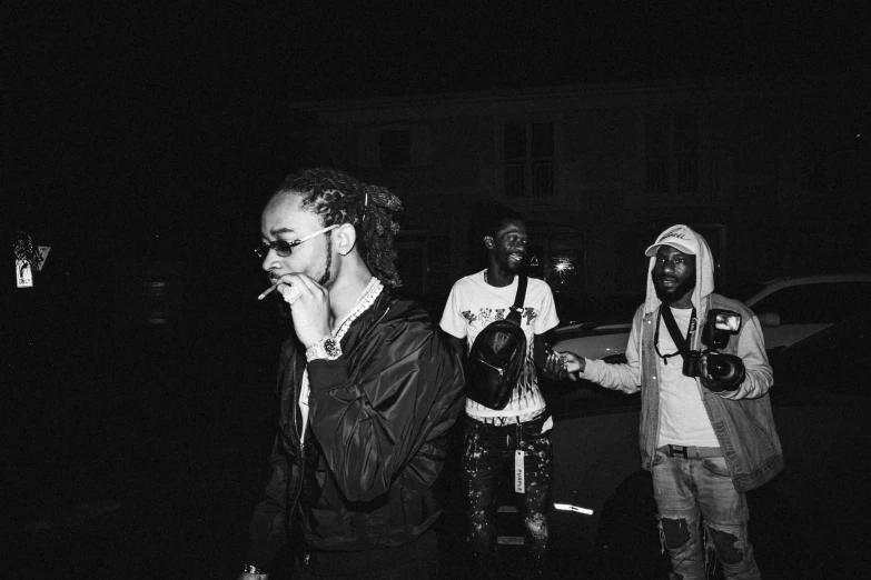 three black people stand with backpacks in the dark