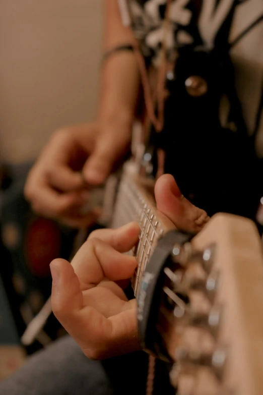 two hands are on a guitar and one hand is holding a pick up