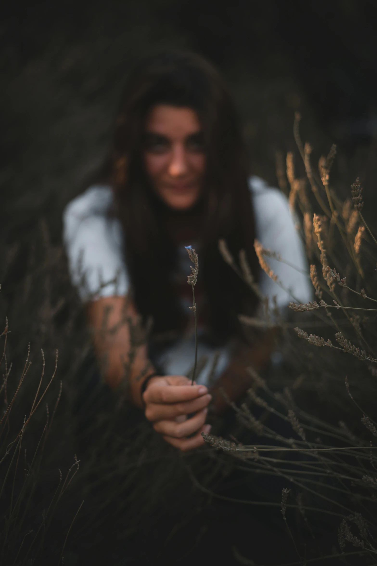 a woman sitting in the grass holding a plant