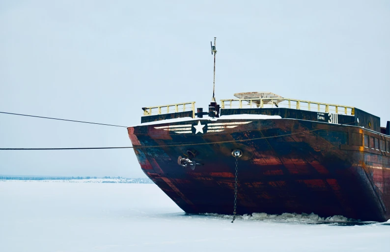 a large rusty boat sits on an ice covered lake