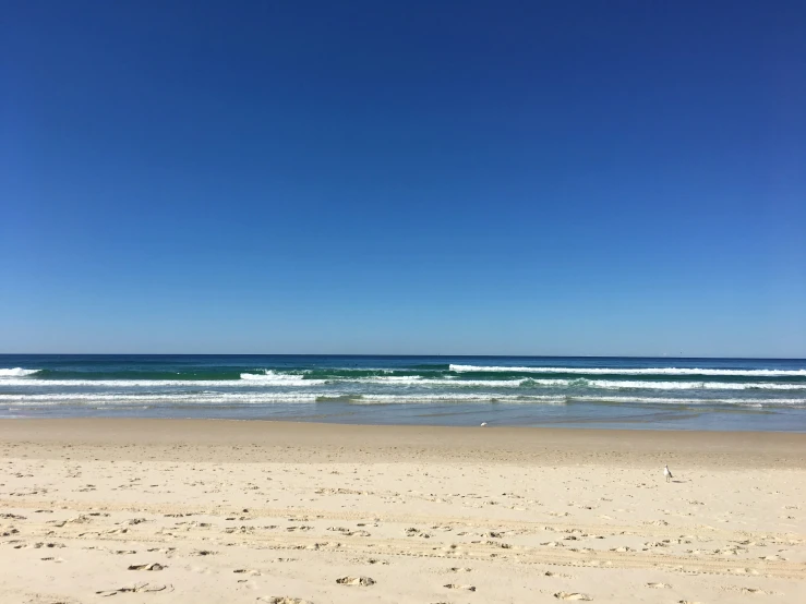 the ocean on the beach has blue skies