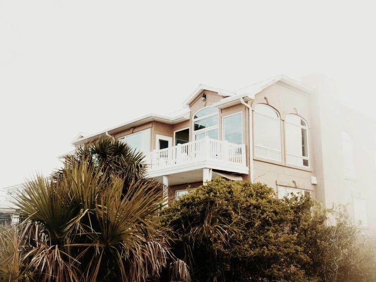 a house next to bushes and trees with fog