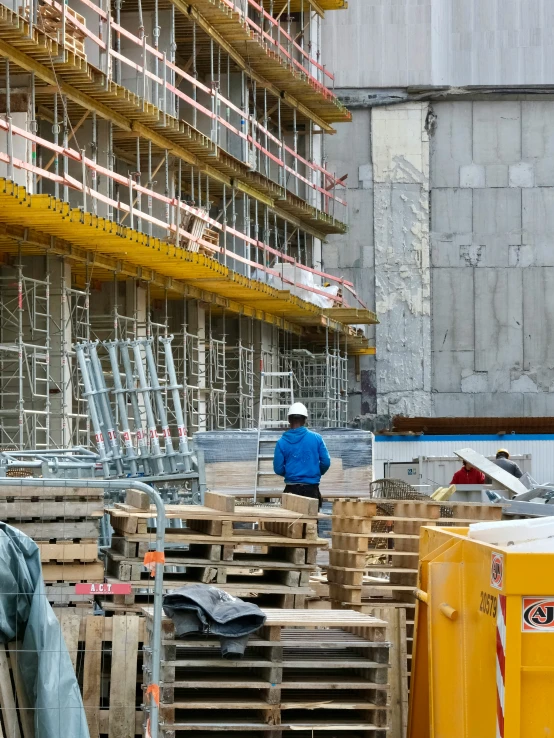 man in blue jacket standing on wooden pallets