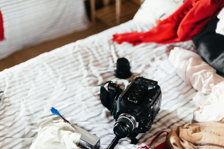 the camera is laying on a bed next to a pile of clothes