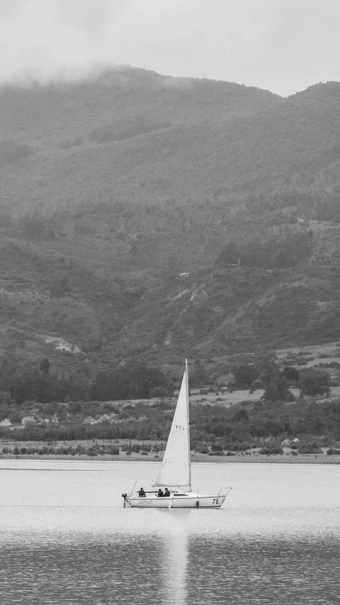 a sail boat on the water in front of hills