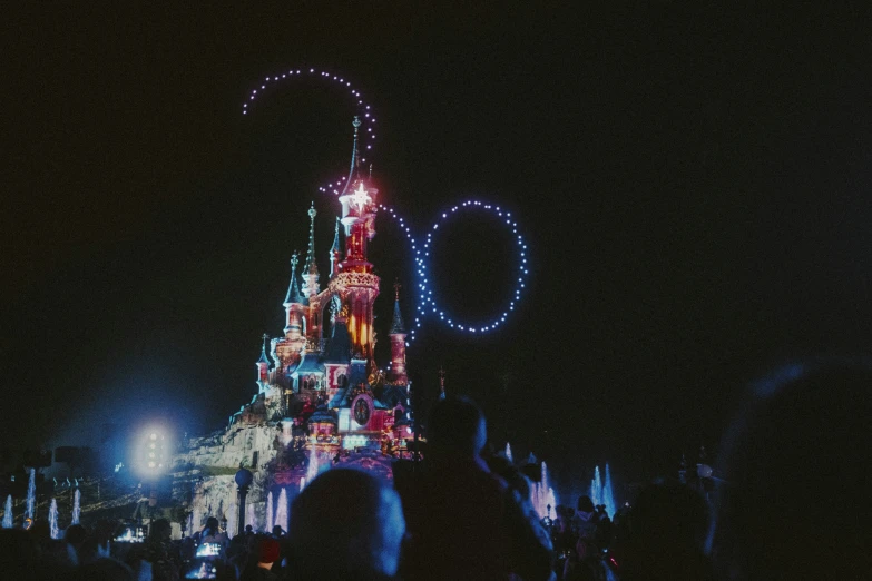 people are in front of the disney castle lit up at night