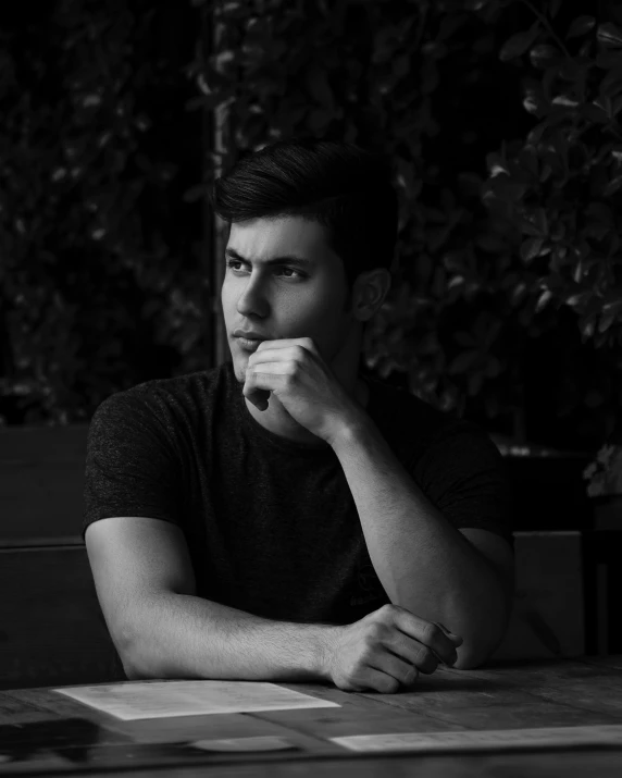 the young man is sitting at the table in the black and white po