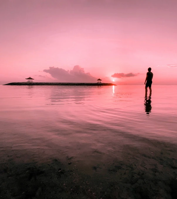 a person standing in the water at sunset