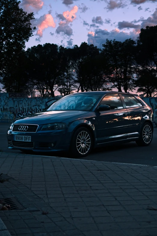 a grey car on the street with trees in the background