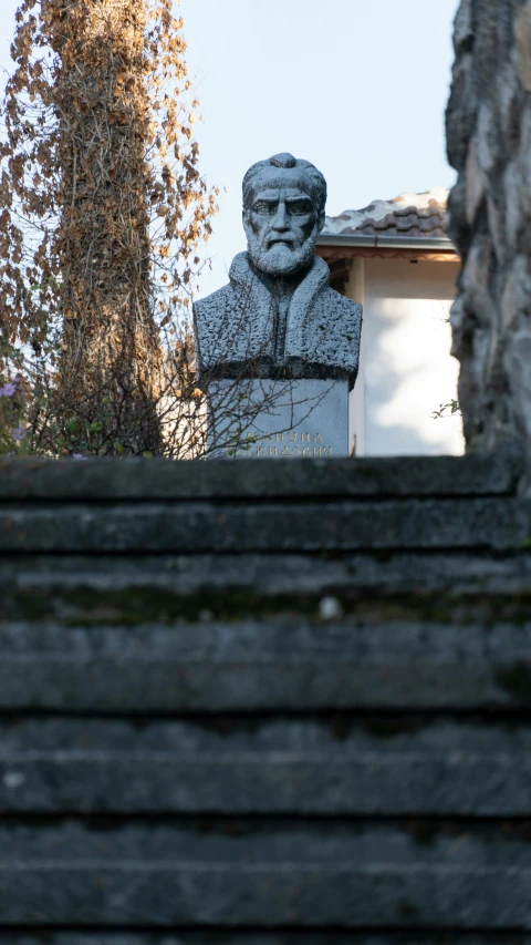 a statue of aham on a hill top by a house