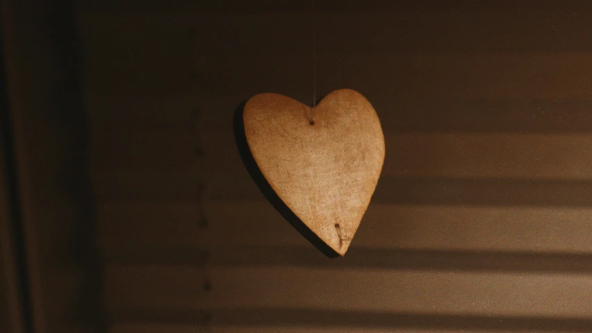 there is a small wooden heart hanging from the wall