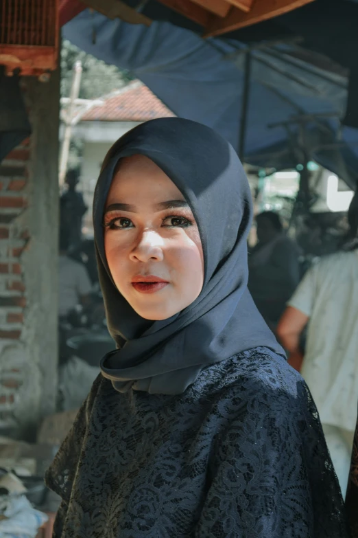 a woman wearing a black shawl standing under a umbrella