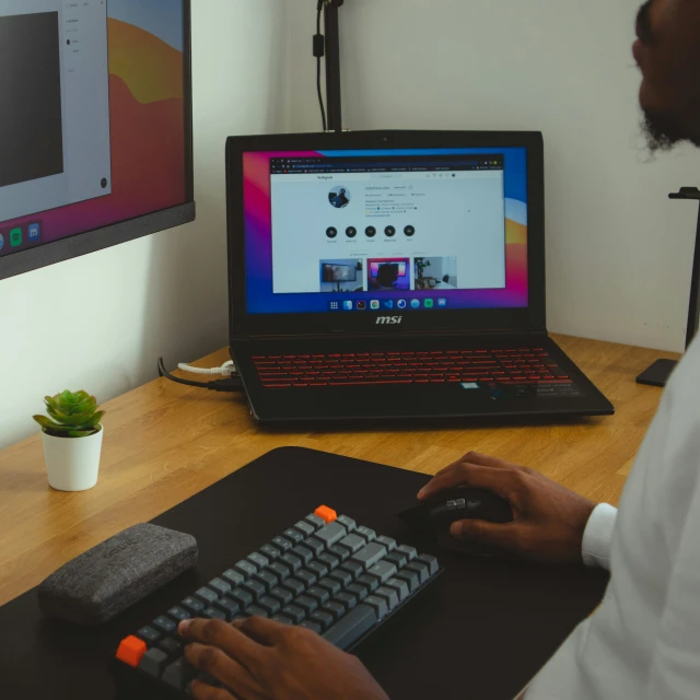 a man works on a laptop, and is using the keyboard