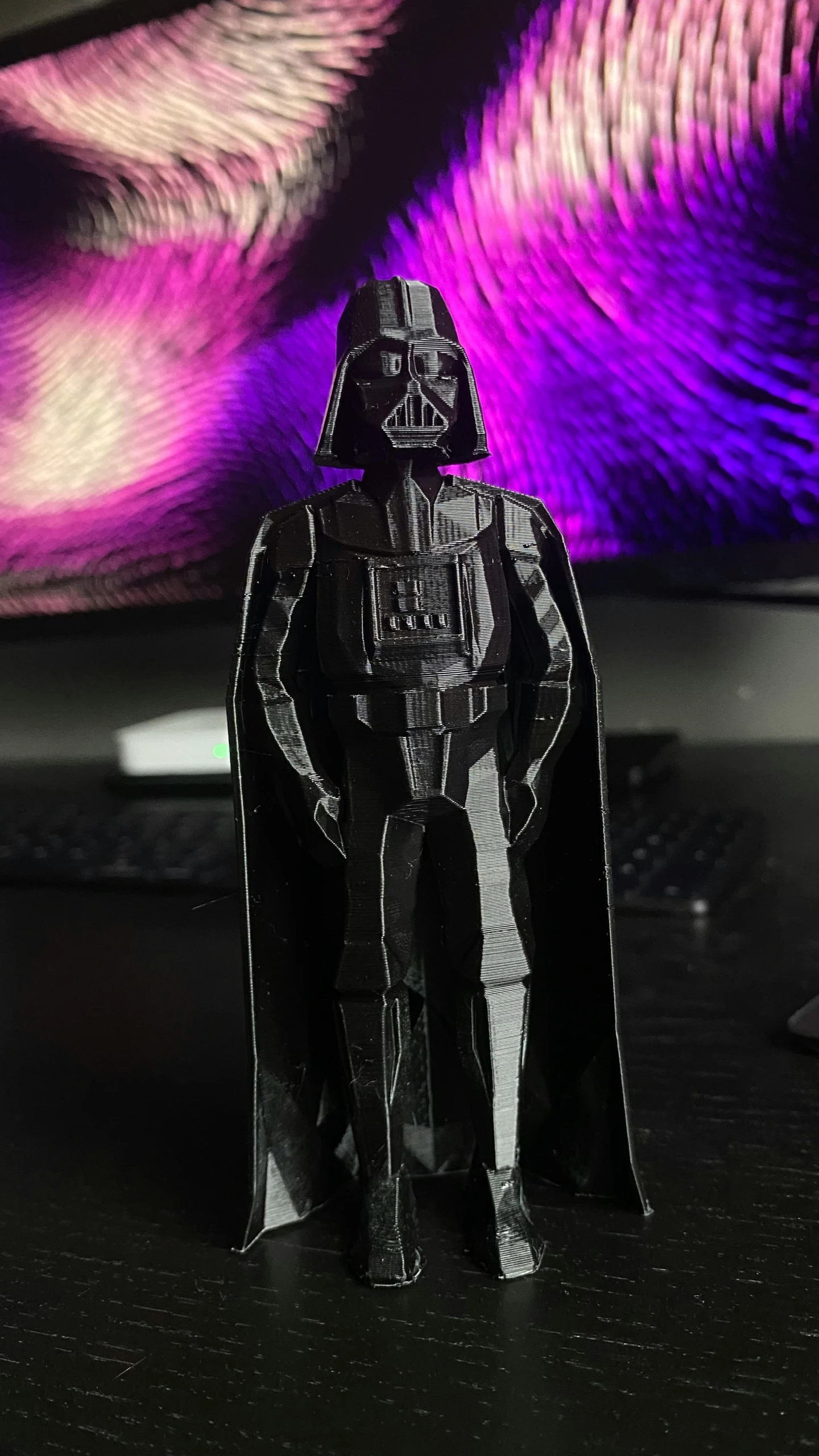 a black darth vader paper toy sitting on a desk