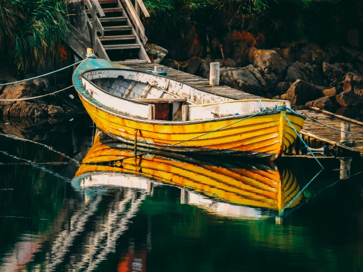 a yellow boat docked at a dock surrounded by green trees