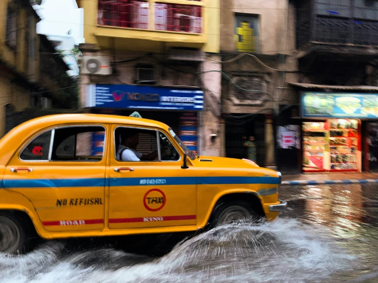 a yellow car driving through a flooded street