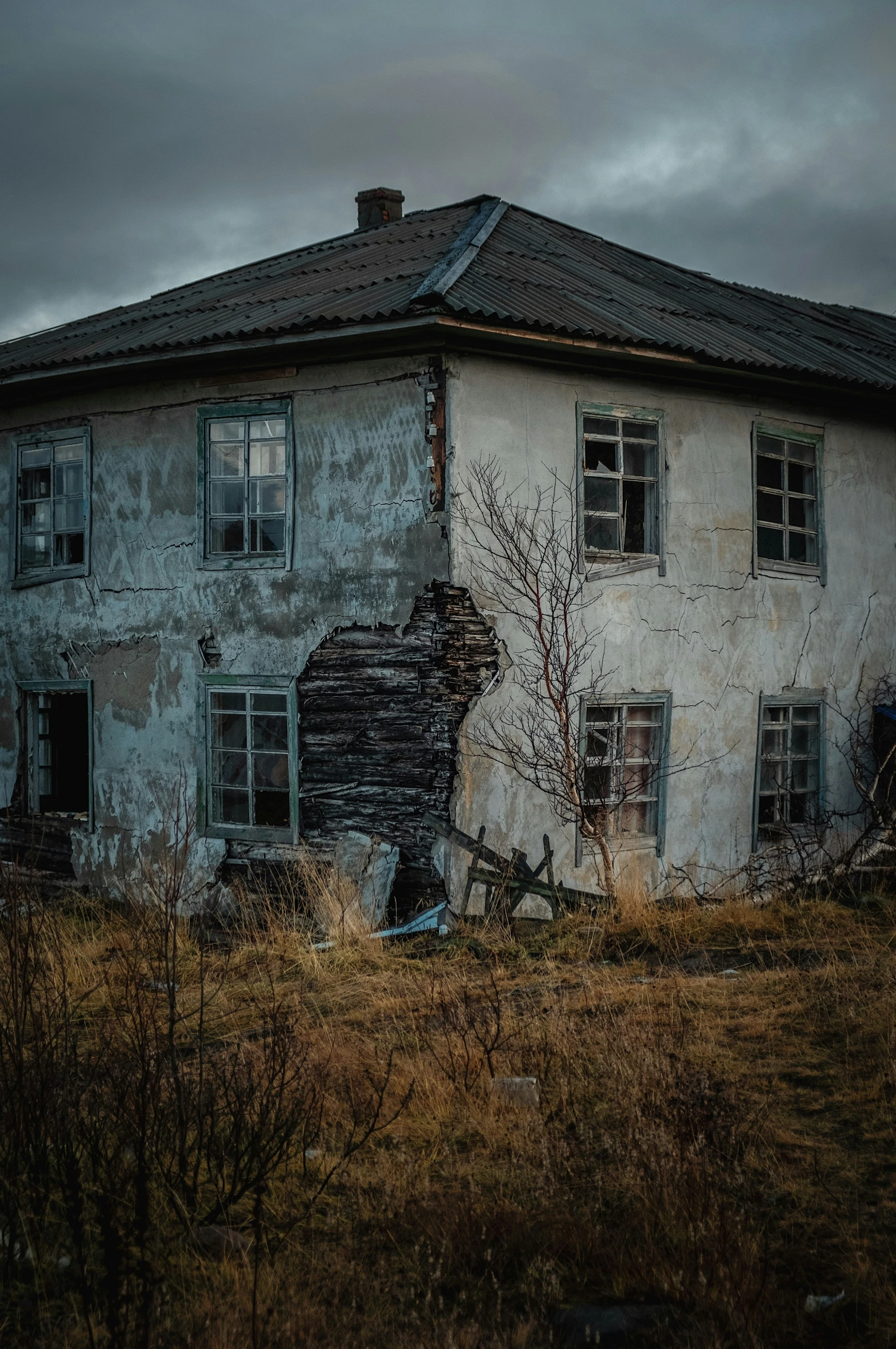 an old, run down, abandoned white house sits in a field