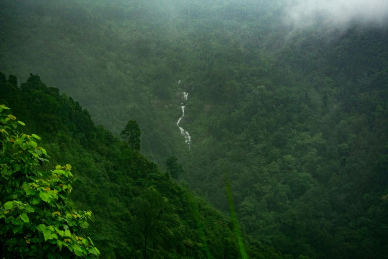 a large waterfall near the top of a forested hill