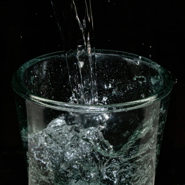 a glass filled with water and a clock in the background