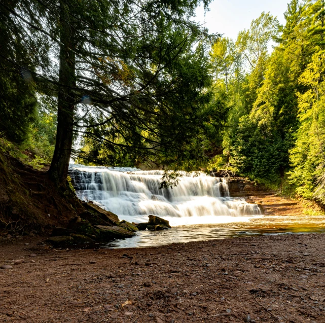 a waterfall with water cascading down it surrounded by trees