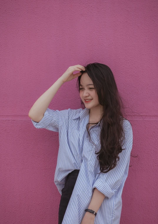 an attractive woman posing in front of a pink wall